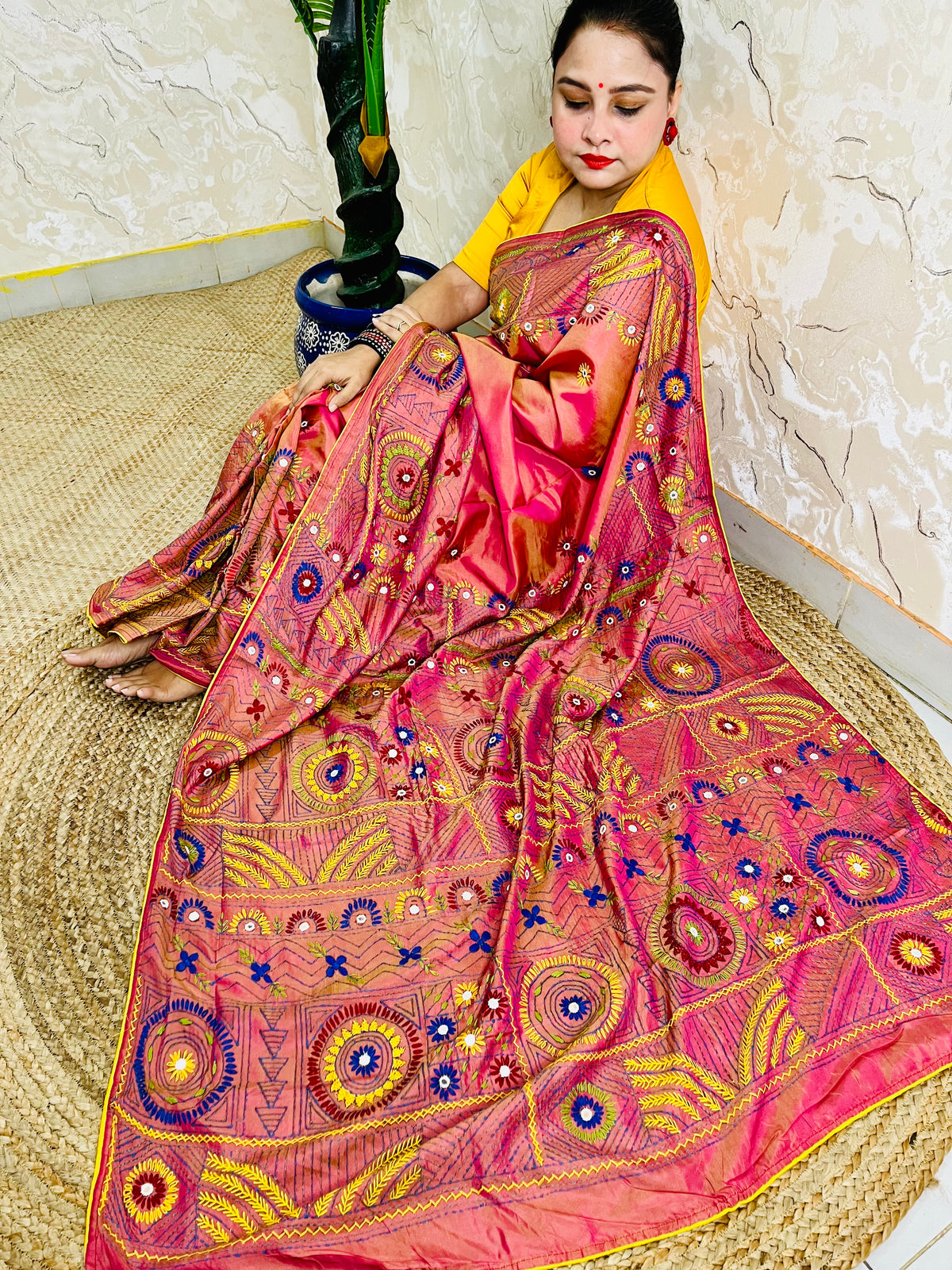 Woman seated in coral pink Lambani embroidered saree, draped pallu view
