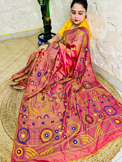 Woman seated in coral pink Lambani embroidered saree, draped pallu view