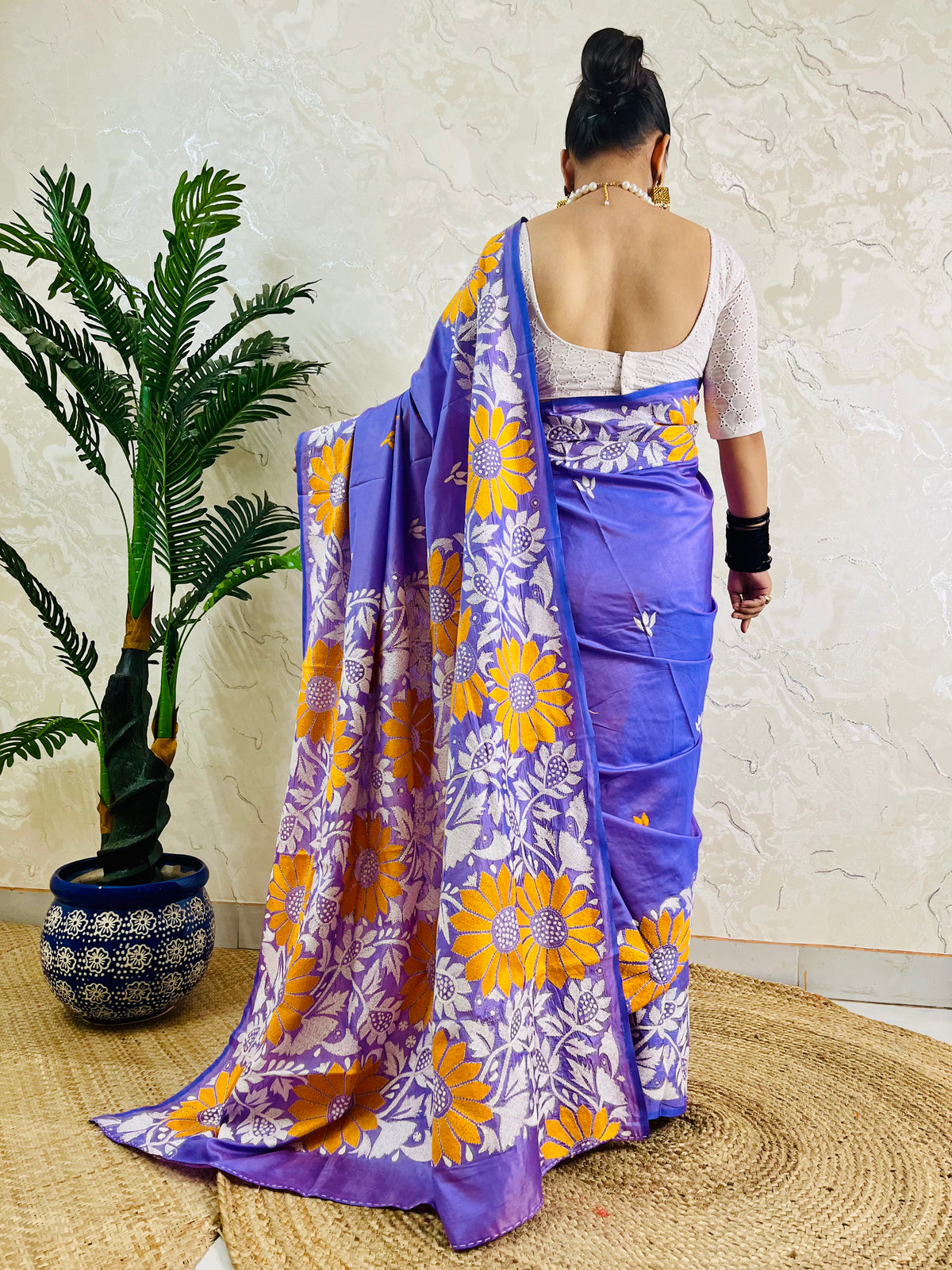 Rear view displaying the lavender violet handwoven traditional saree and the expansive yellow sunflower Katha stitch artwork across the back.