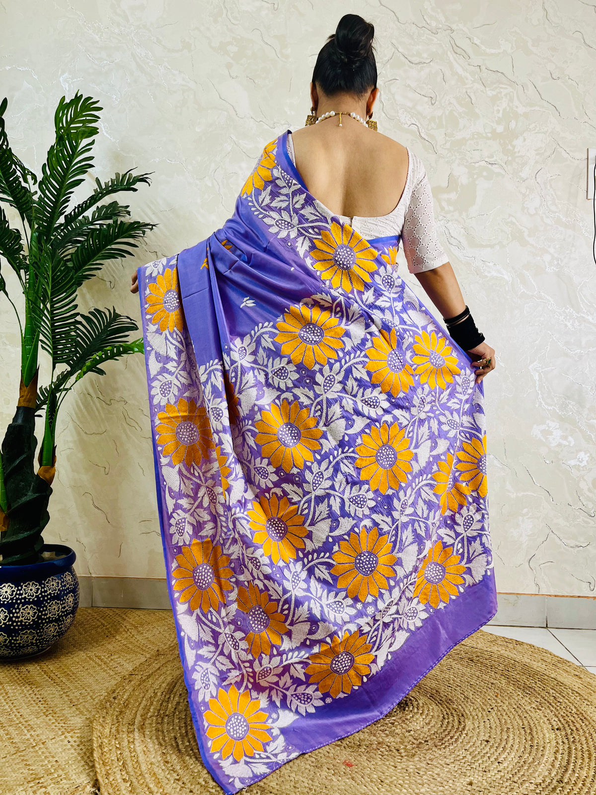 Rear view displaying the lavender violet handwoven traditional saree and the expansive yellow sunflower Katha stitch artwork across the back.