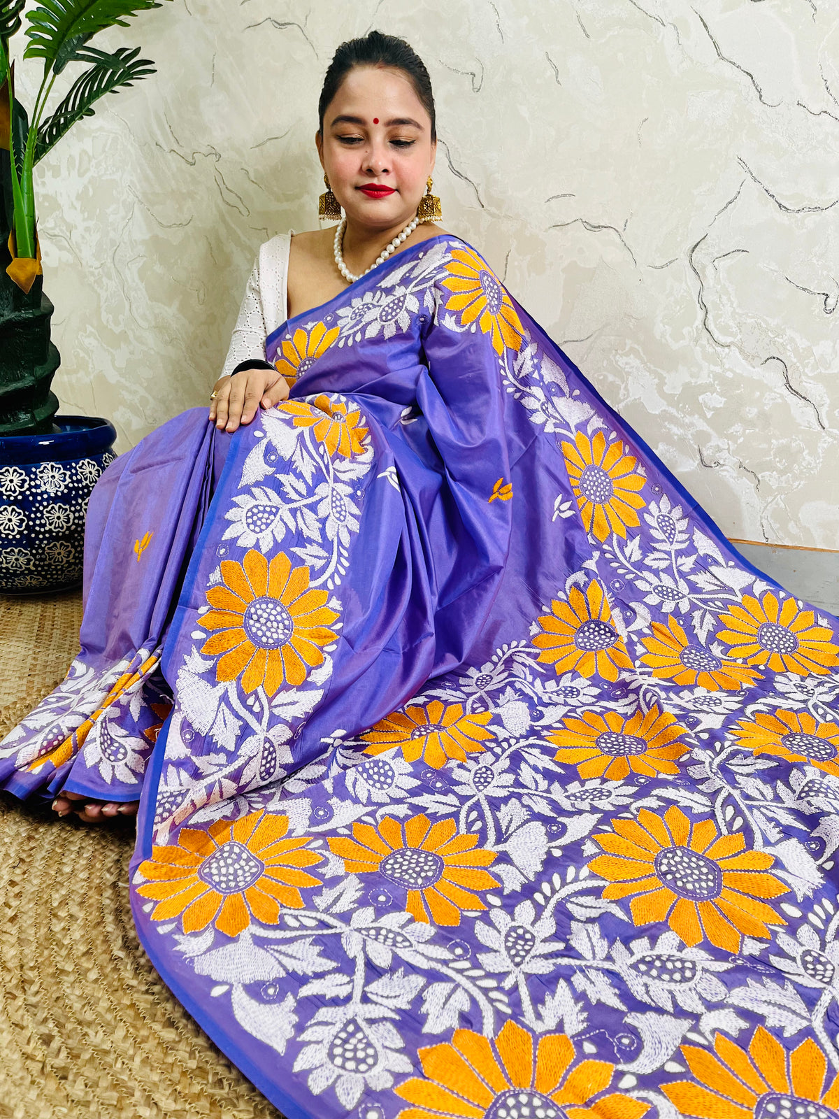 Seated model draped in the exclusive handmade saree, displaying the detailed contrast thread work on the pallu and body.