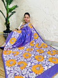 High-angle sitting view of the spread-out lavender violet saree, showcasing the intricate white leaf vines and vibrant golden sunflower embroidery.