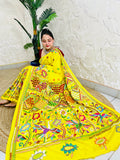 Woman sitting gracefully while draped in the vibrant sunny yellow Nakshi Katha saree, showcasing the densely embroidered, multi-colored border and pallu