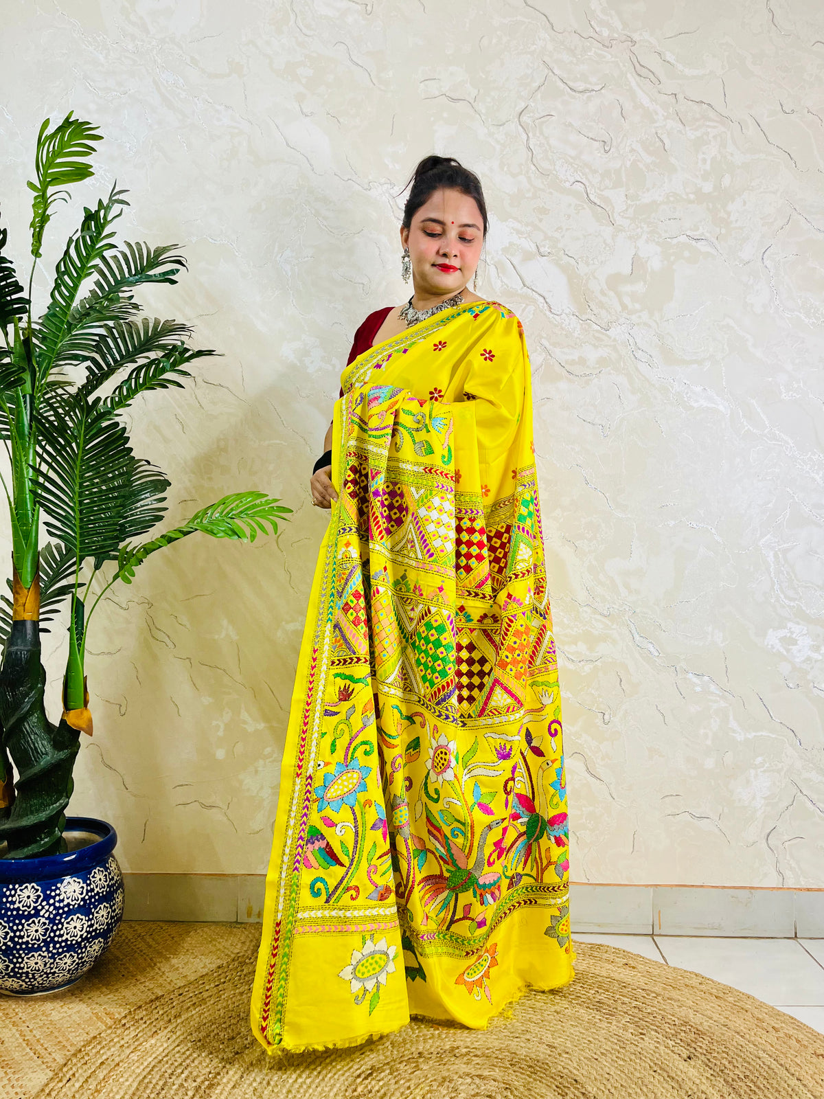 Front view of a woman elegantly modeling the exclusive handmade yellow Nakshi Katha traditional saree, displaying the vibrant, unreplicable ethnic thread work