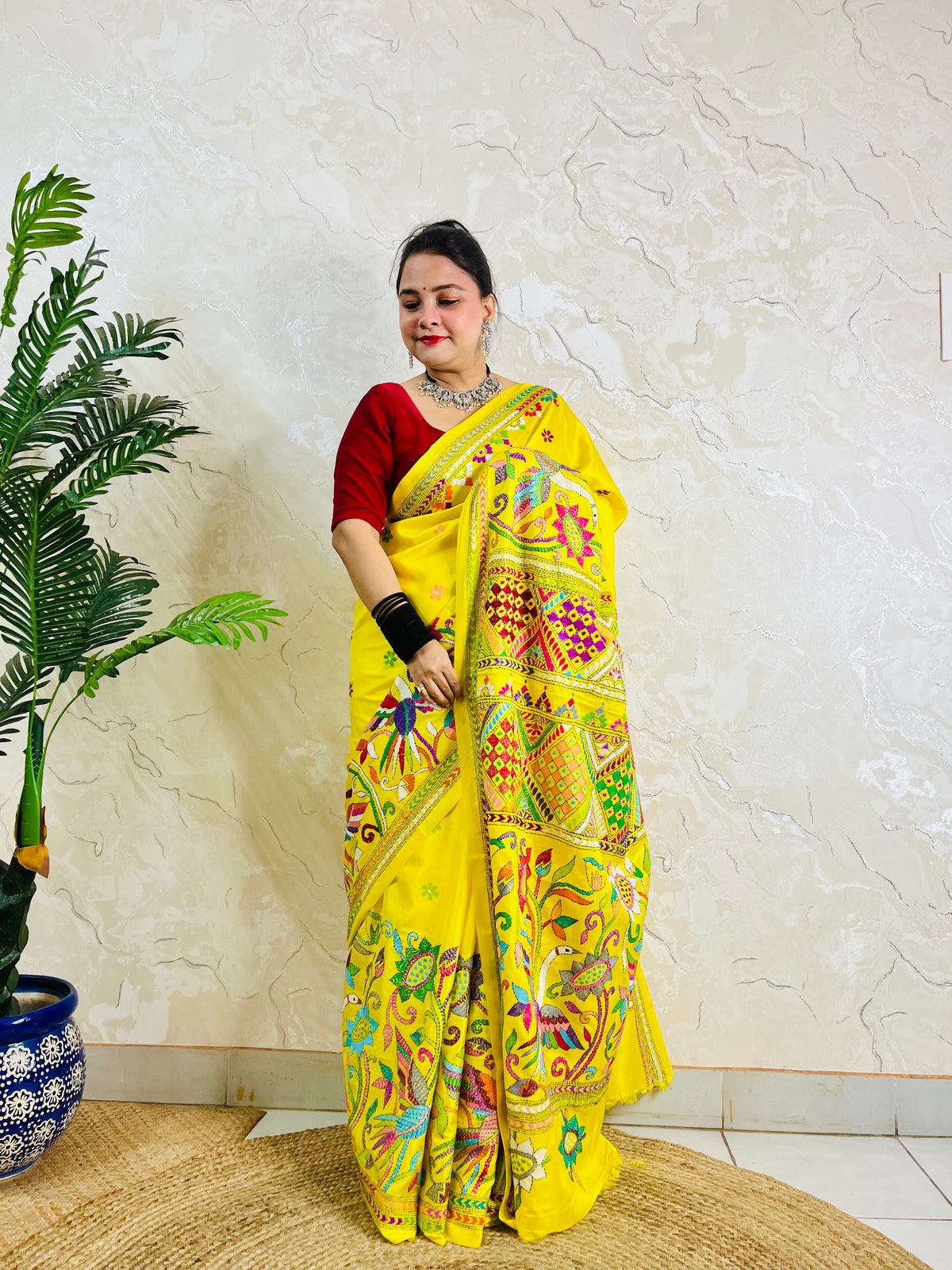 Front view of a woman elegantly modeling the exclusive handmade yellow Nakshi Katha traditional saree, displaying the vibrant, unreplicable ethnic thread work