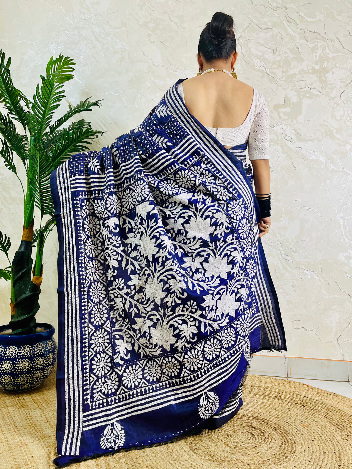 Rear view displaying the drape of the navy blue handwoven traditional saree and the contrast white Katha stitch patterns across the back