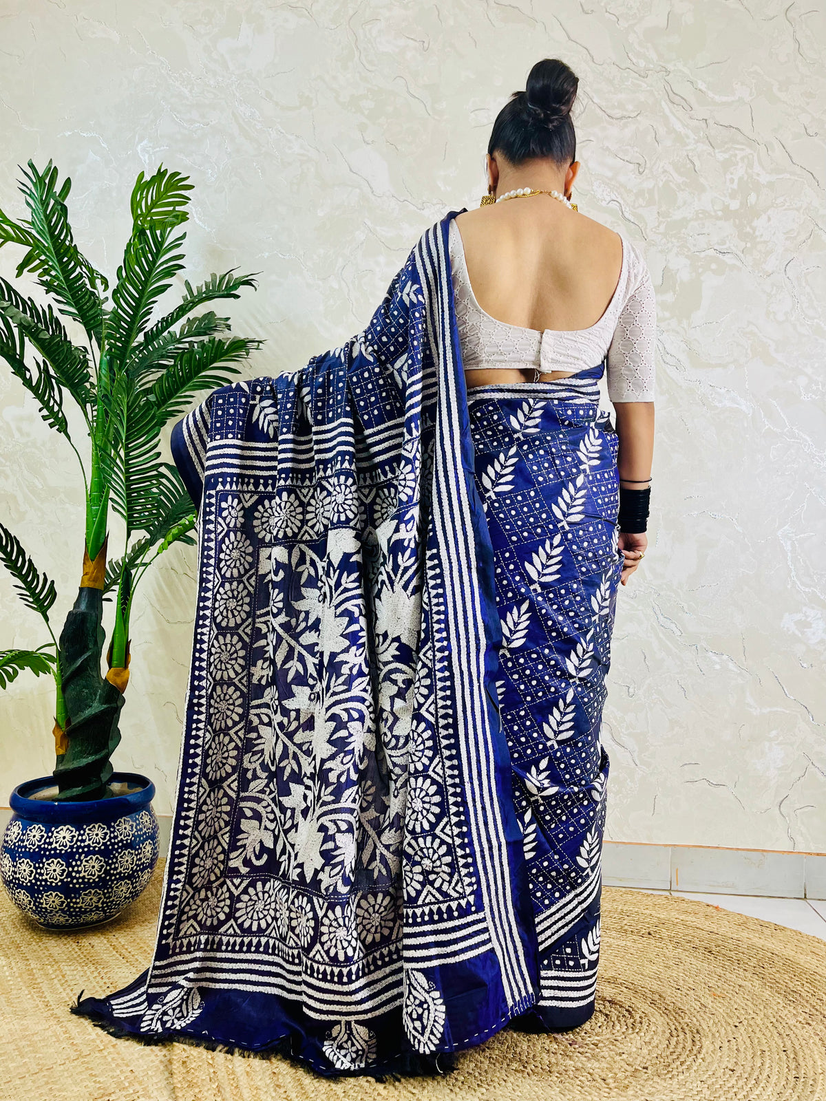 Rear view displaying the drape of the navy blue handwoven traditional saree and the contrast white Katha stitch patterns across the back