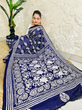 Woman sitting draped in the navy blue Kantha silk saree, spreading out the dense white floral vine embroidery on the pallu.