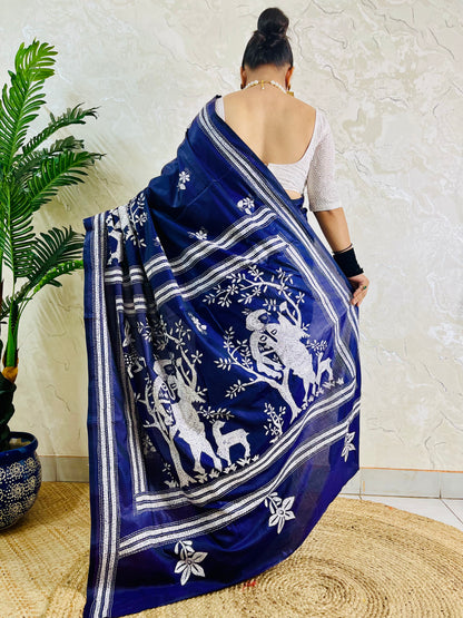 Rear view of woman draped in the navy blue handcrafted saree, highlighting the expansive village tapestry embroidered on the pallu.