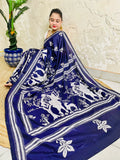 High-angle sitting pose showcasing the spread-out Santhal flute player and deer motif pallu embroidery on navy Bangalore silk.