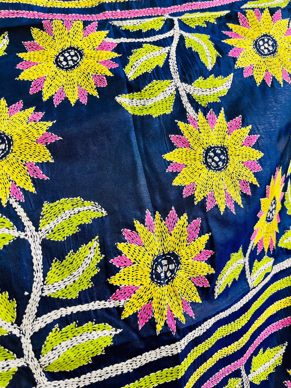 Close-up of yellow sunflower Kantha running stitch embroidery with lime leaves on navy blue silk