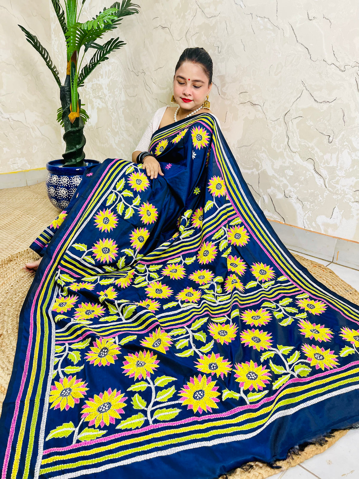 Seated drape of navy blue Kantha stitch saree with yellow sunflower motifs and scattered small flowers