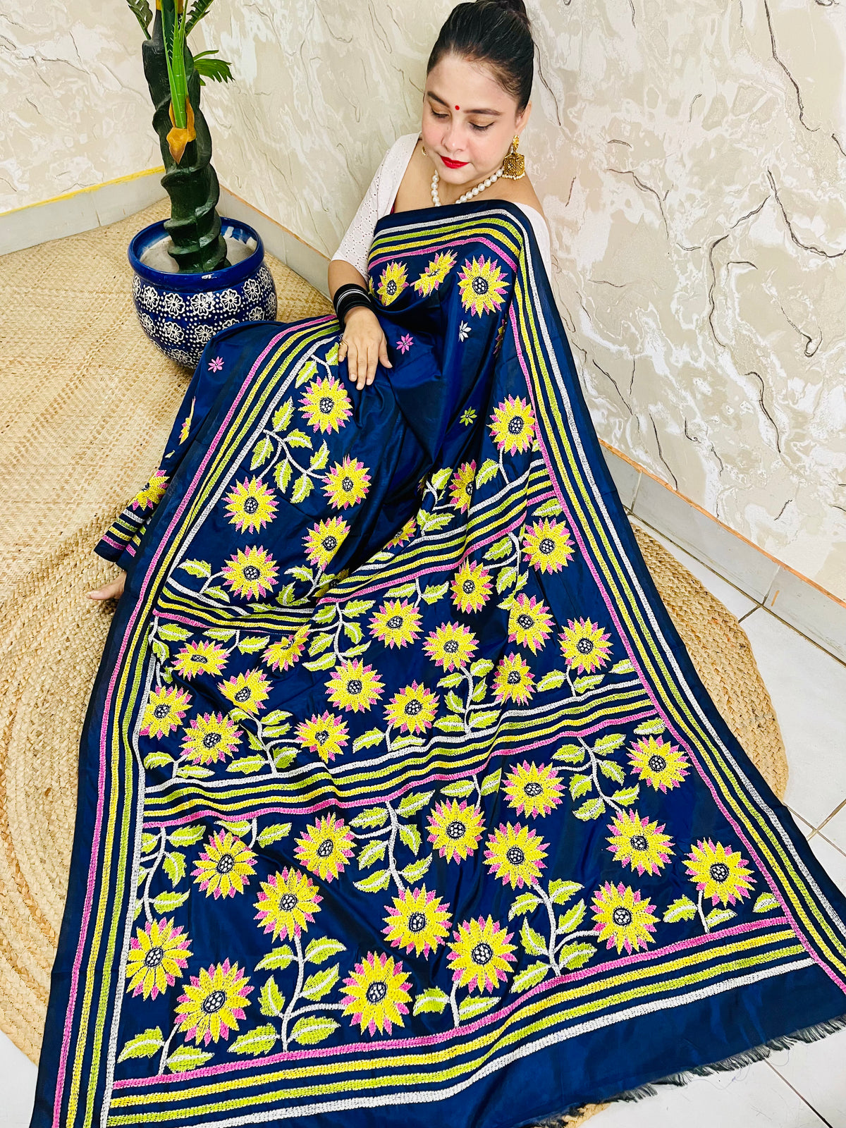 Seated drape of navy blue Kantha stitch saree with yellow sunflower motifs and scattered small flowers