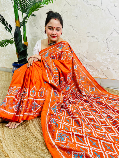 Seated pose showing orange saree pallu with Gujarati stitch geometric pattern