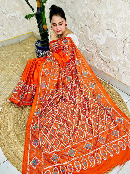 Seated pose showing orange saree pallu with Gujarati stitch geometric pattern