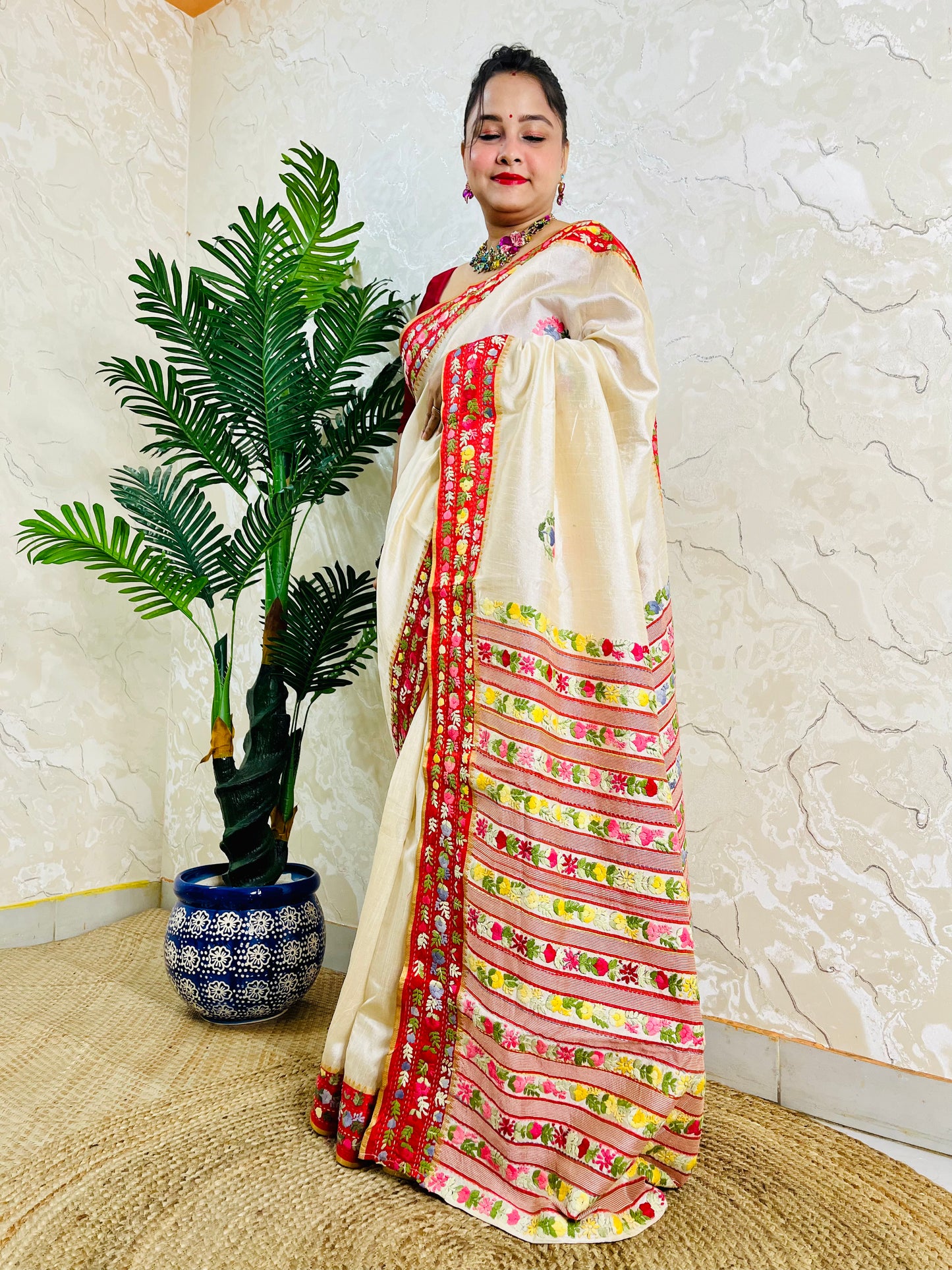 Front standing view of Parsi Gara handwoven Semi Muga Silk saree with red velvet border and multicolour floral embroidery — heirloom saree by Desi Aadat