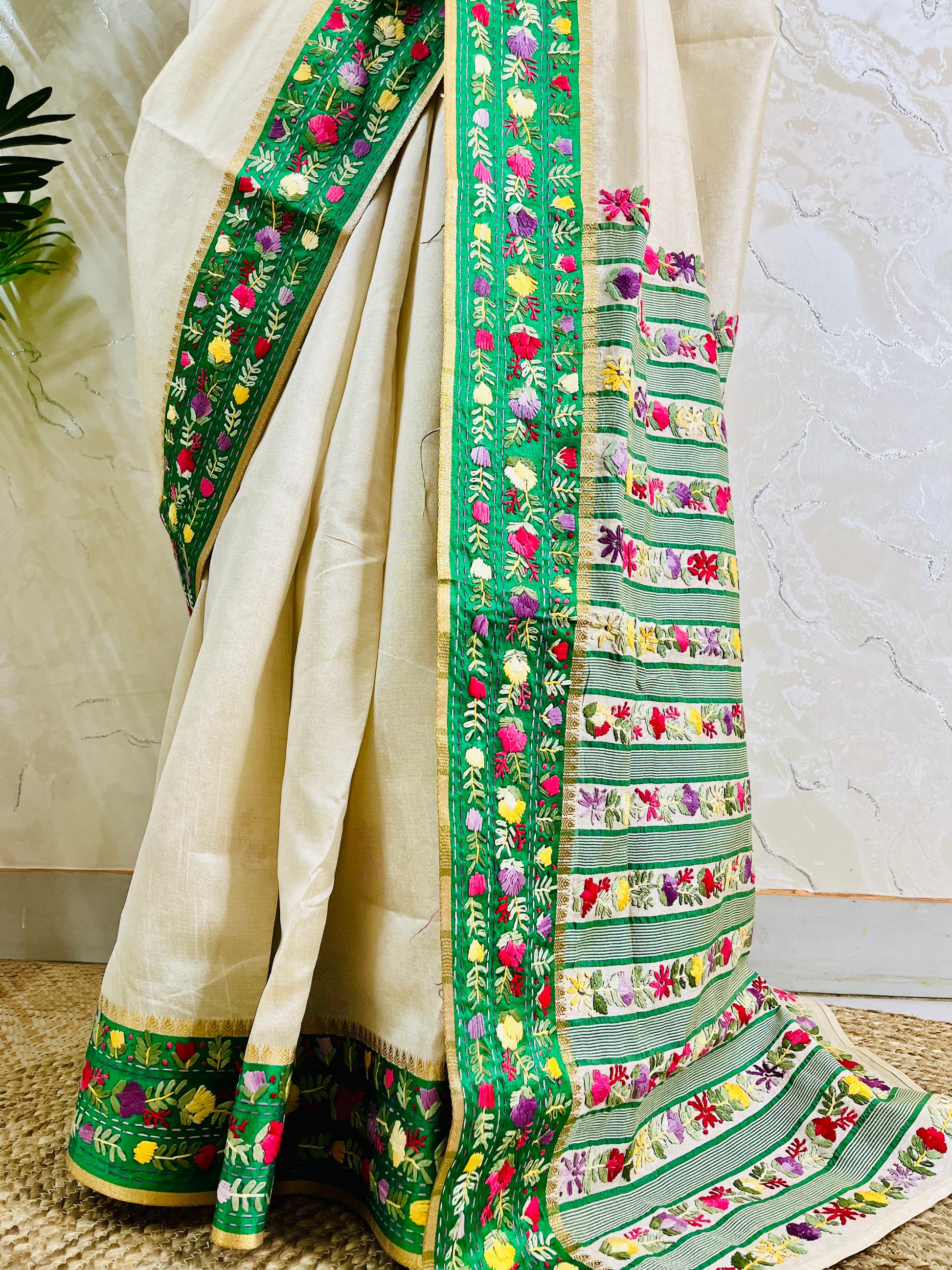 Bottom view of emerald green velvet Parsi Gara embroidered border with Kardana work and multicolour floral hand embroidery on ivory Semi Muga Silk saree — Desi Aadat