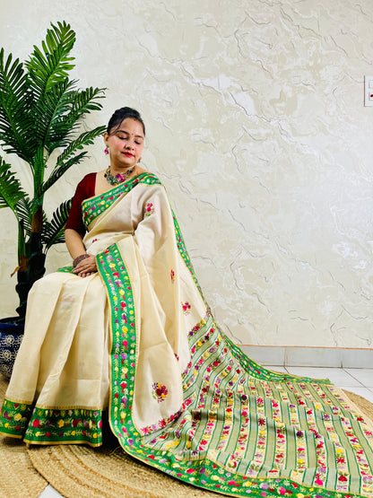 Side sitting view of Parsi Gara handwoven ivory Semi Muga Silk saree with emerald green velvet border and full multicolour floral garden pallu with woven stripe body — Desi Aadat