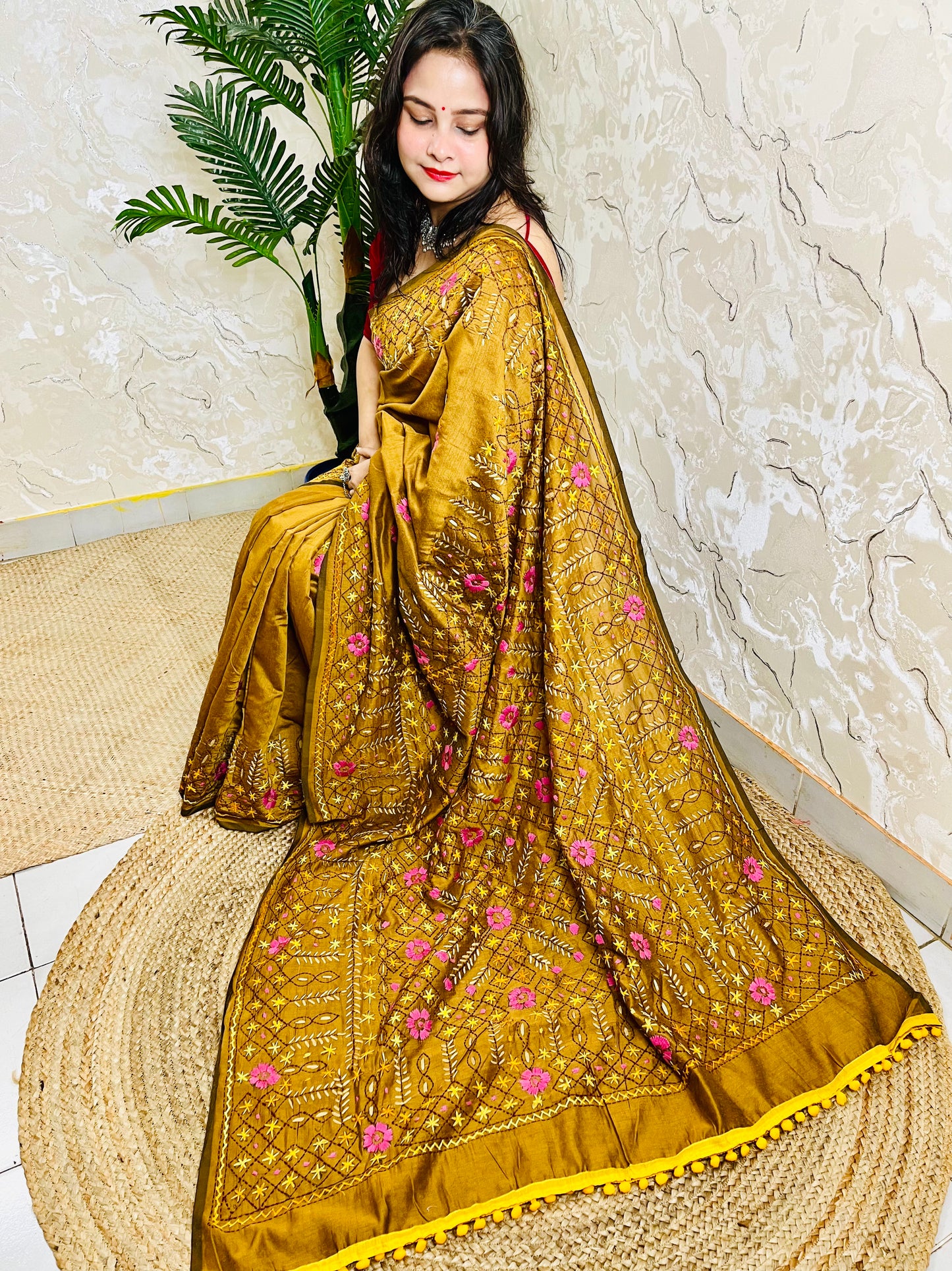 All-over Jali Parsi Gara golden brown Chanderi silk cotton saree with pink floral embroidery and yellow pompom border — side sitting view, Desi Aadat