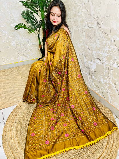 All-over Jali Parsi Gara golden brown Chanderi silk cotton saree with pink floral embroidery and yellow pompom border — side sitting view, Desi Aadat