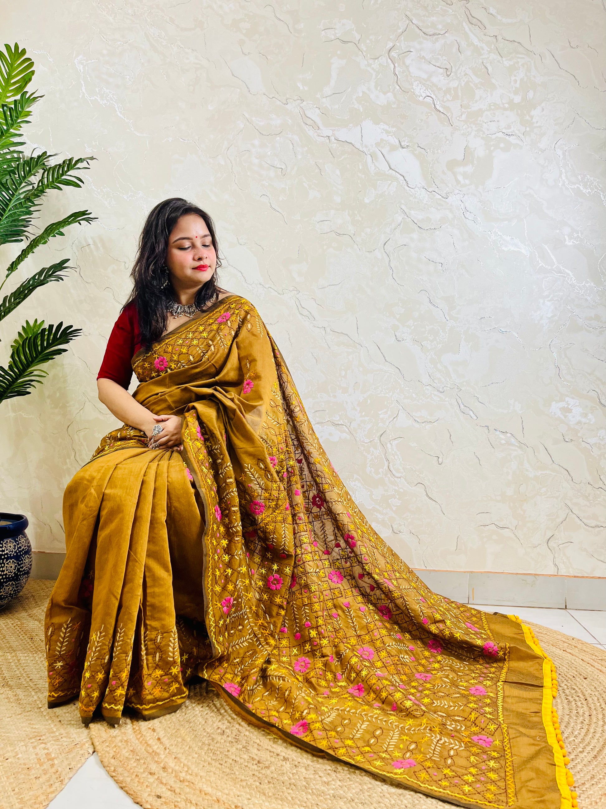 All-over Jali Parsi Gara golden brown Chanderi silk cotton saree with pink floral embroidery and yellow pompom border — side sitting view, Desi Aadat