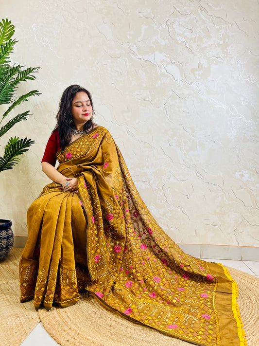 All-over Jali Parsi Gara golden brown Chanderi silk cotton saree with pink floral embroidery and yellow pompom border — side sitting view, Desi Aadat