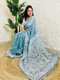 Handmade Lucknowi Chikankari pastel dusty blue pure organza silk saree with dense white jaal and floral embroidery — sitting drape view, Desi Aadat