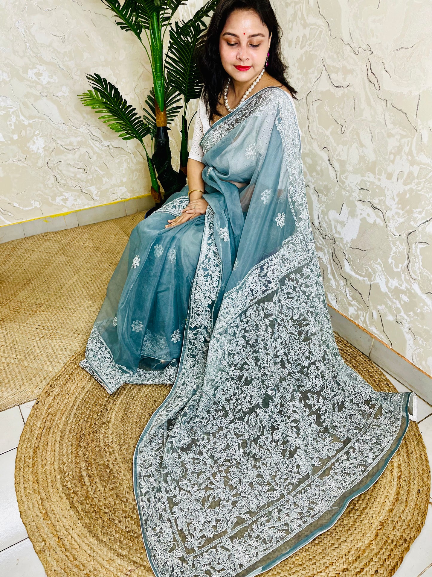 Handmade Lucknowi Chikankari pastel dusty blue pure organza silk saree with dense white jaal and floral embroidery — sitting drape view, Desi Aadat