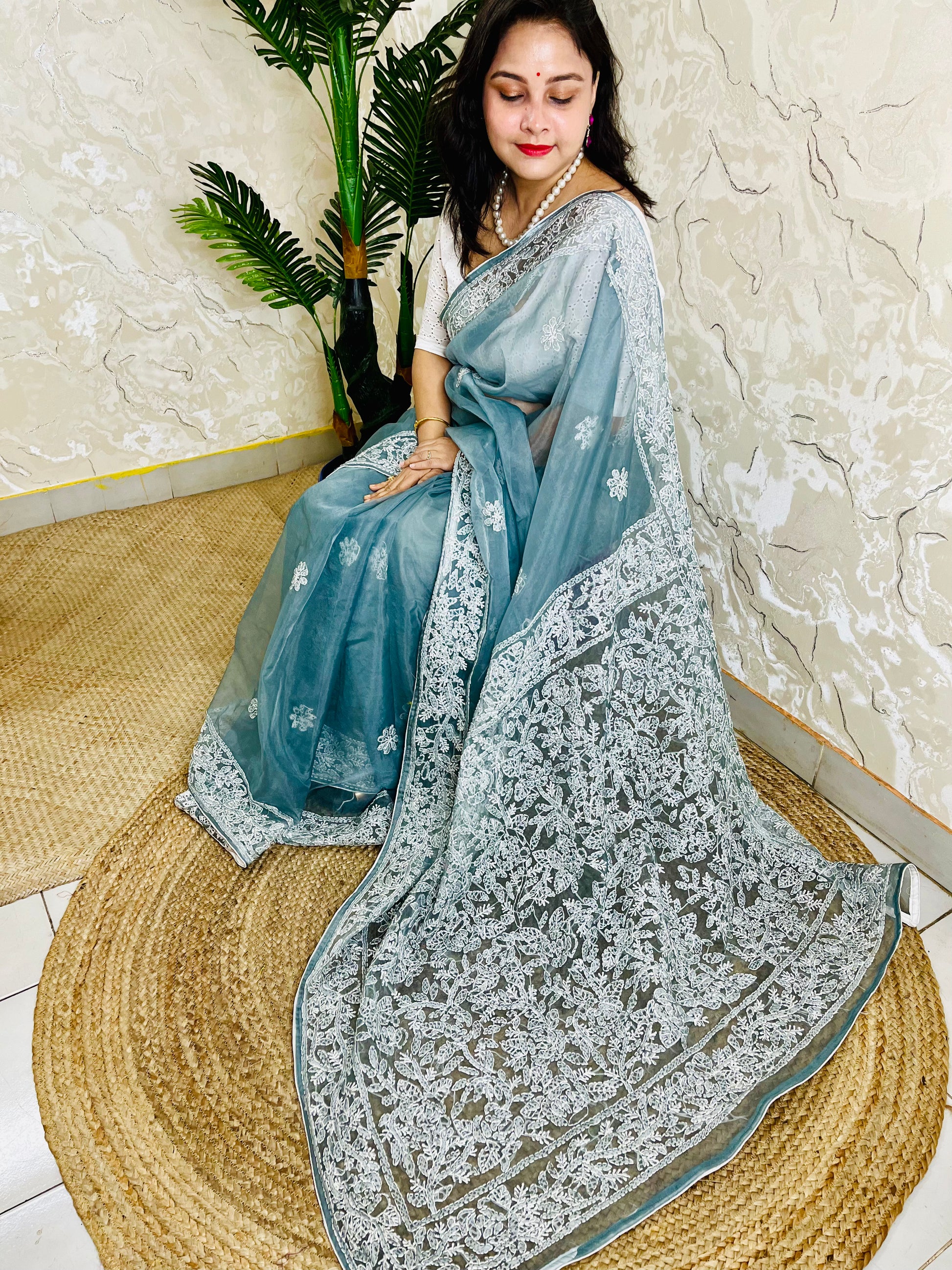 Handmade Lucknowi Chikankari pastel dusty blue pure organza silk saree with dense white jaal and floral embroidery — sitting drape view, Desi Aadat