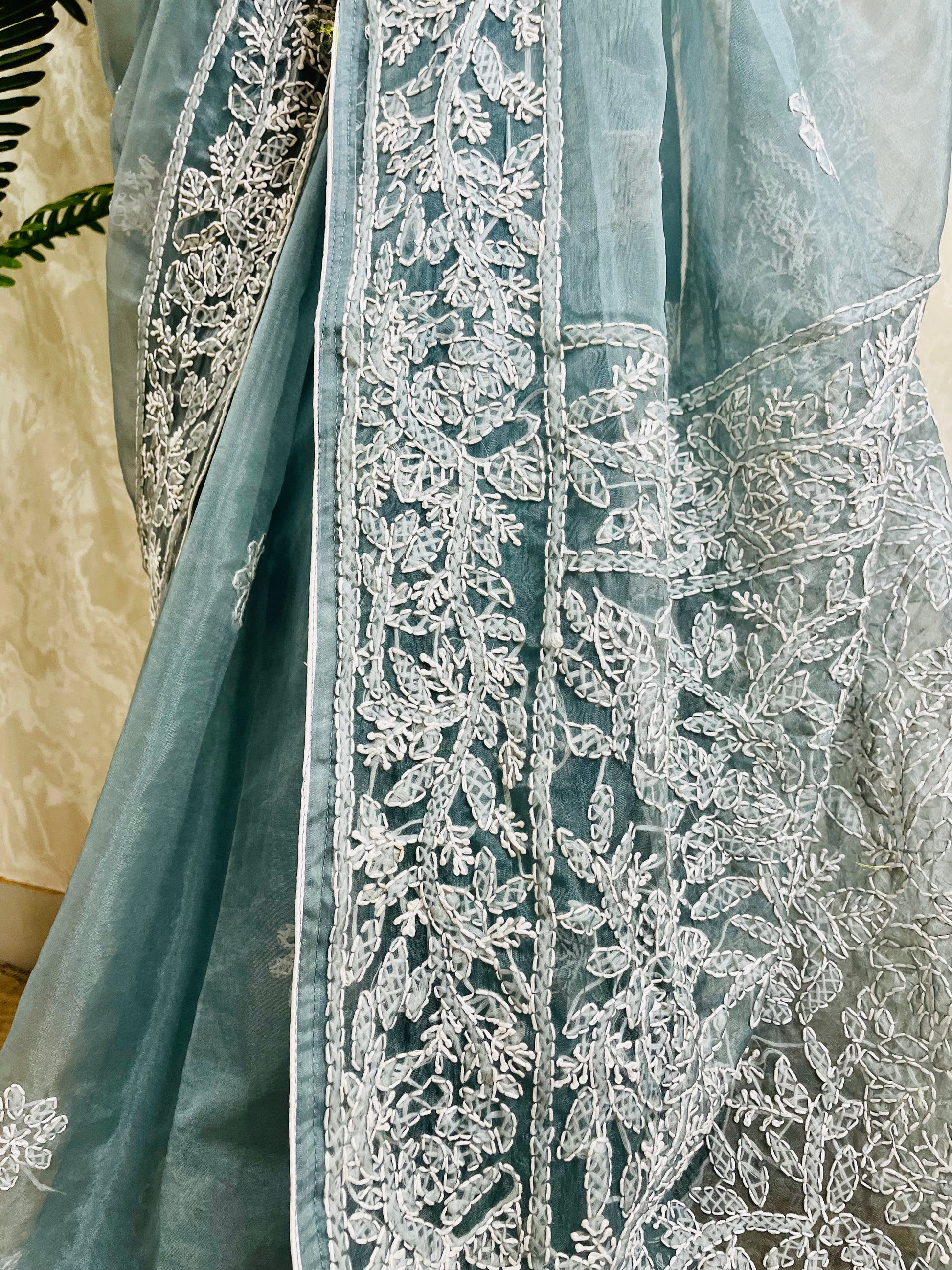 Close-up of structured white Lucknowi Chikankari jaal, vine, and shadow stitch hand embroidery on pastel dusty blue pure organza silk saree — Desi Aadat