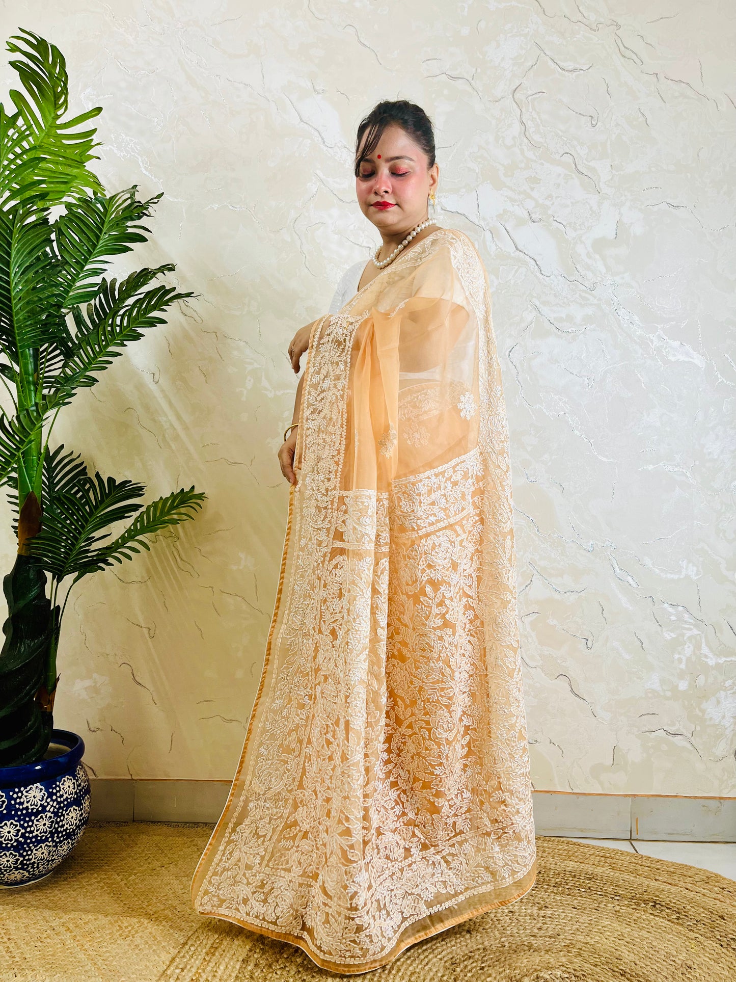 Pastel peach orange Chikankari handstitched organza silk saree with full white jaal and floral embroidery — side standing view, Desi Aadat