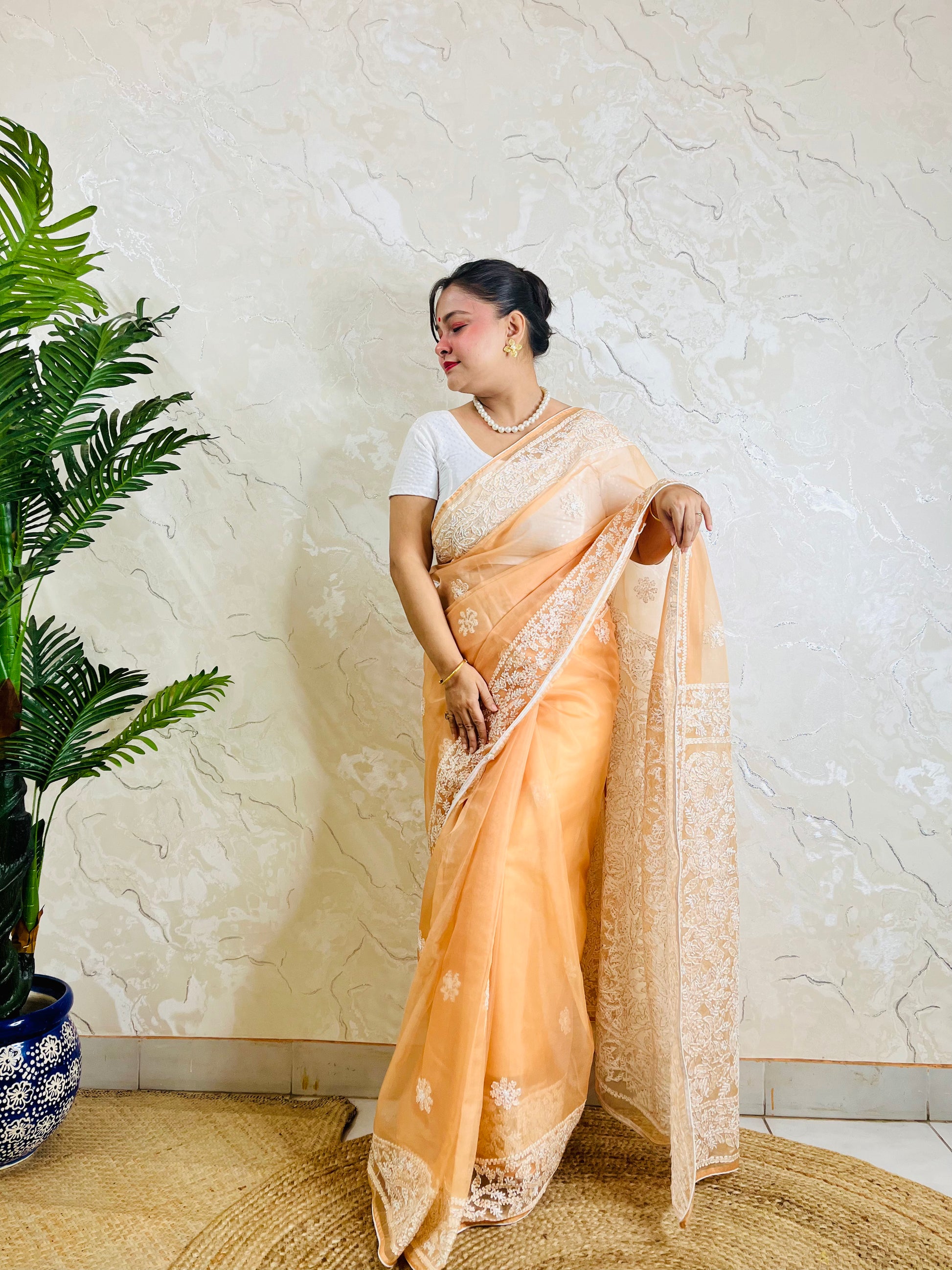Pastel peach orange Chikankari handstitched organza silk saree with full white jaal and floral embroidery — side standing view, Desi Aadat