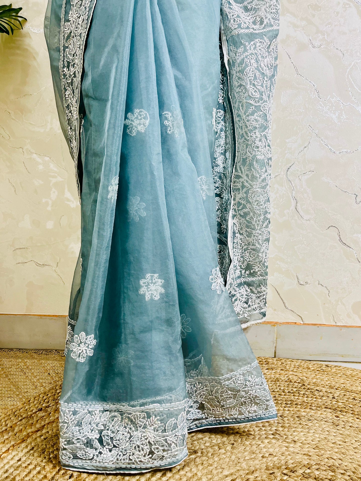 Close-up of dense white Lucknowi Chikankari jaal, shadow stitch, and butti floral hand embroidery on pastel powder blue pure organza silk saree — Desi Aadat