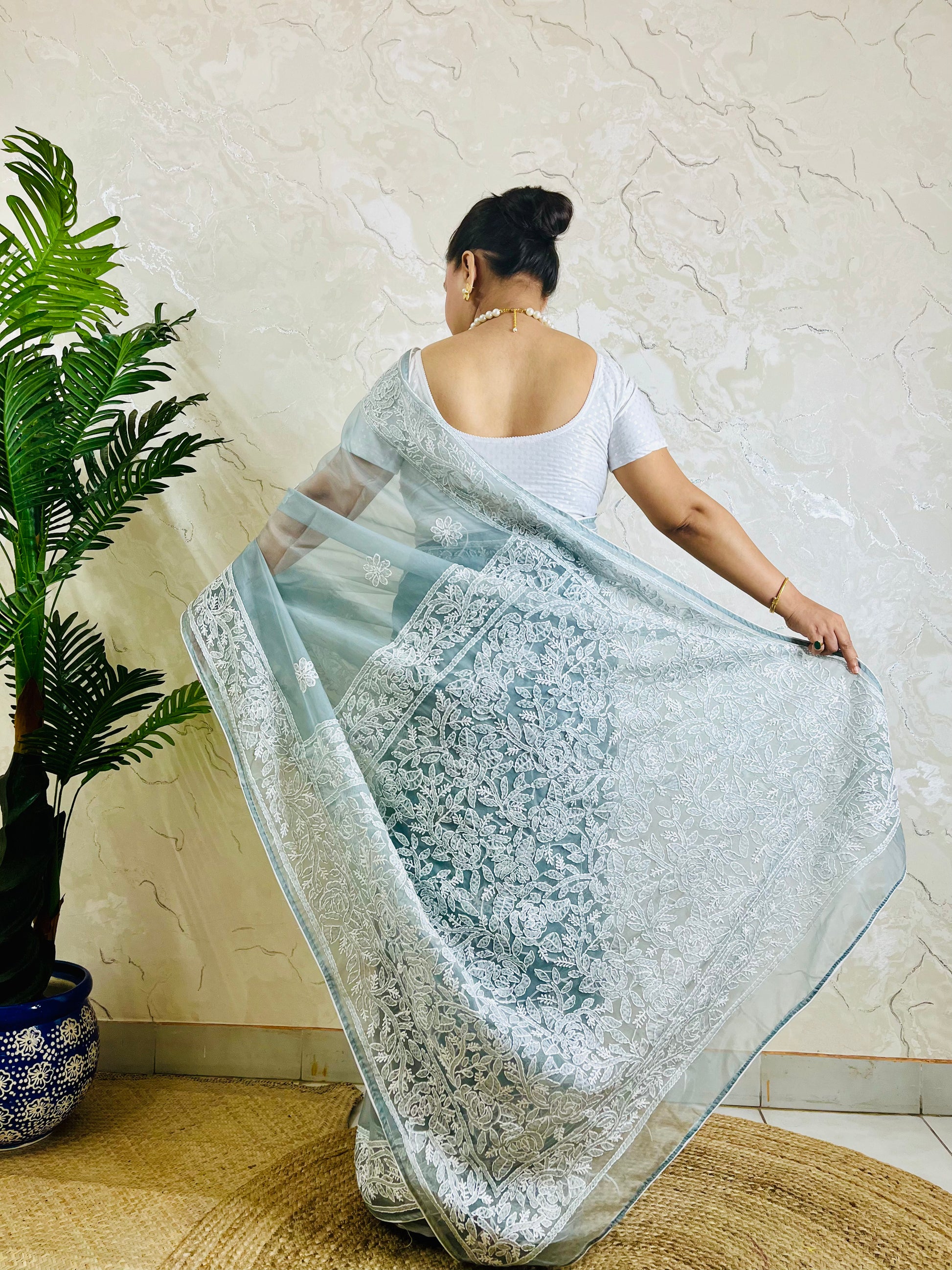 Pastel powder blue Chikankari handstitched organza silk saree with full white jaal embroidery displayed on standing model — pallu view, Desi Aadat