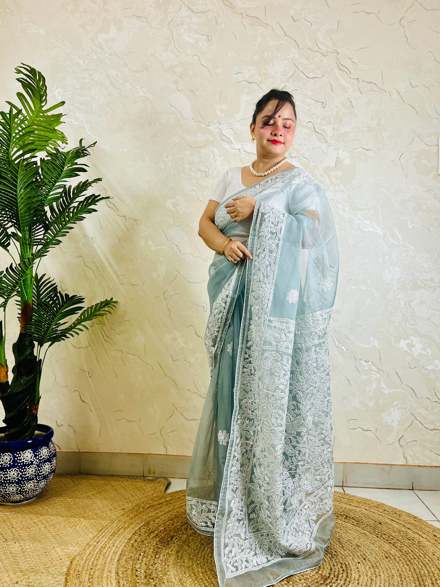 Pastel powder blue Chikankari handstitched organza silk saree with full white jaal embroidery displayed on standing model — pallu view, Desi Aadat