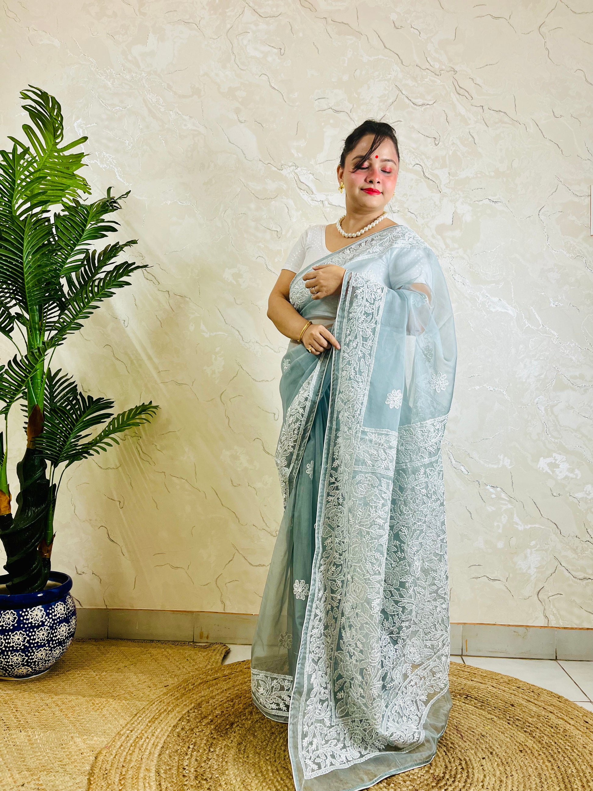 Pastel powder blue Chikankari handstitched organza silk saree with full white jaal embroidery displayed on standing model — pallu view, Desi Aadat