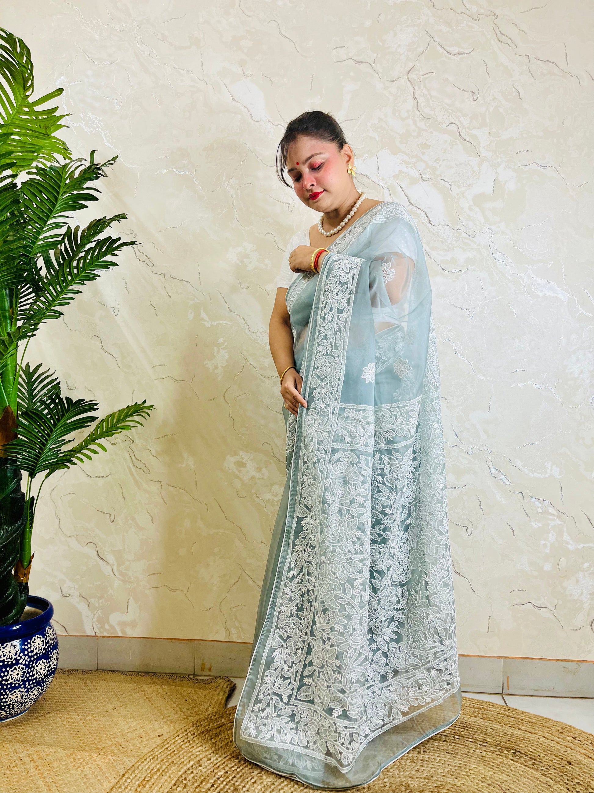 Pastel powder blue Chikankari handstitched organza silk saree with full white jaal embroidery displayed on standing model — pallu view, Desi Aadat