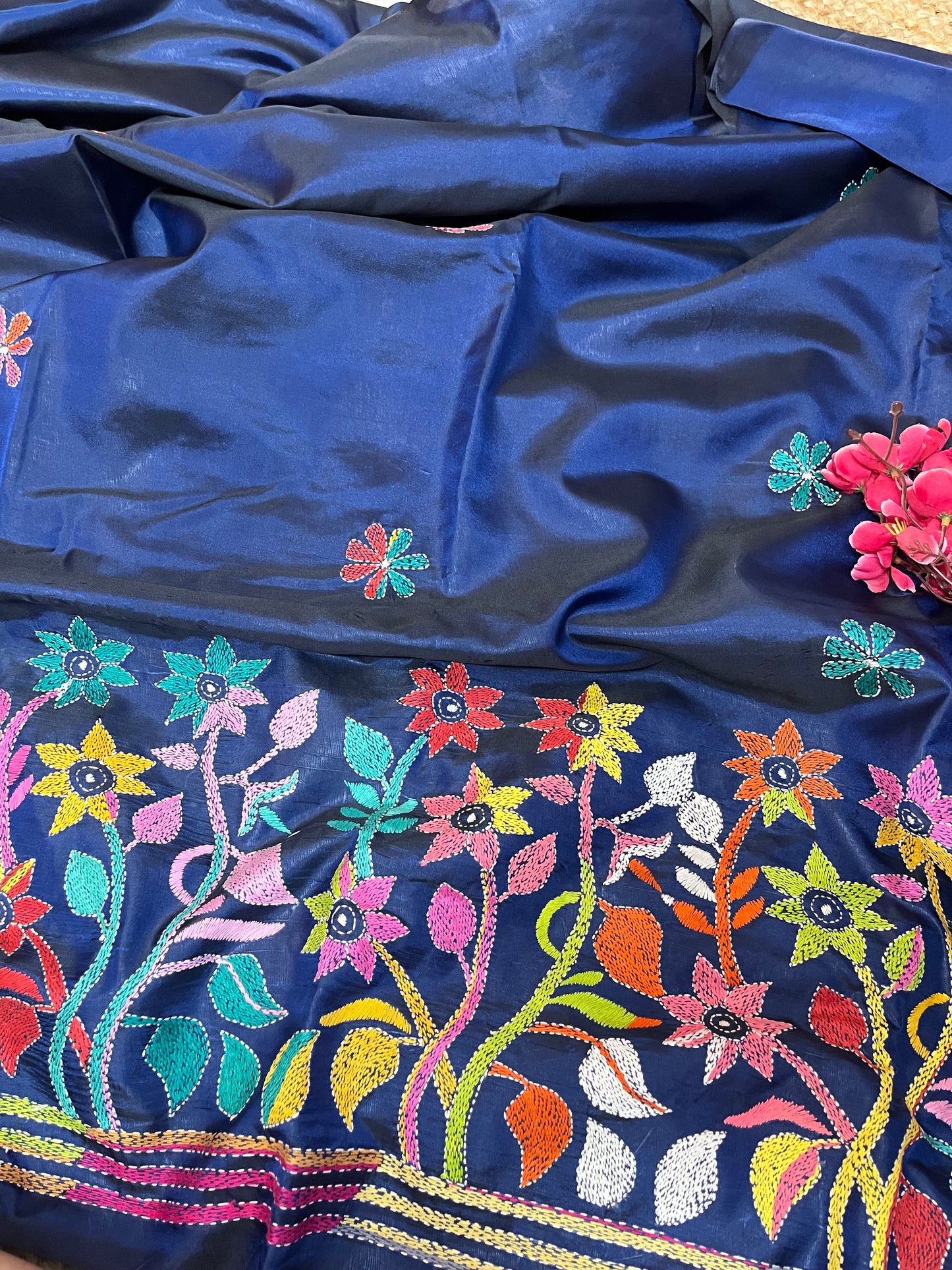Close-up of human figure and floral Kantha embroidery on peacock blue handwoven fabric