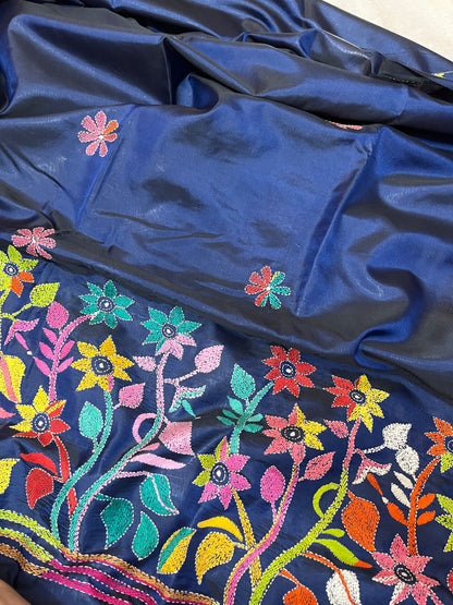 Close-up of human figure and floral Kantha embroidery on peacock blue handwoven fabric