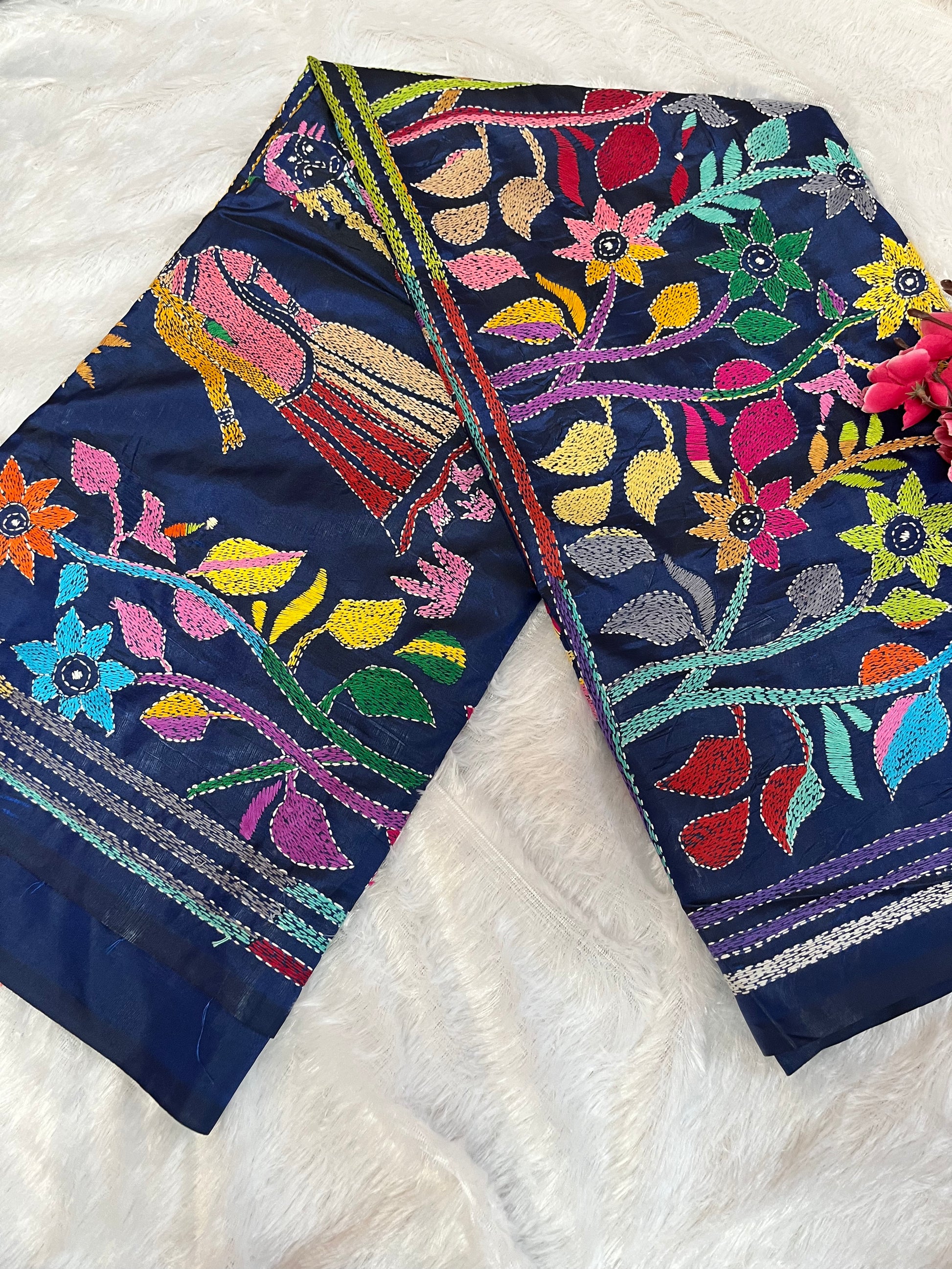 Close-up of human figure and floral Kantha embroidery on peacock blue handwoven fabric