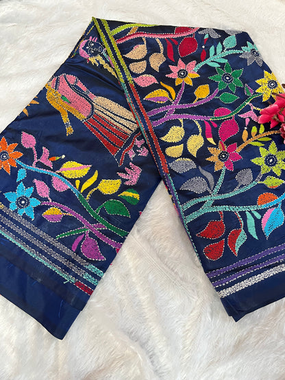 Close-up of human figure and floral Kantha embroidery on peacock blue handwoven fabric