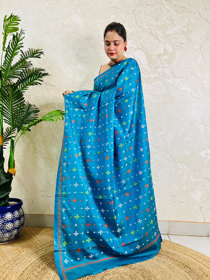 Woman holding peacock blue Kutch work saree pallu showing embroidery detail