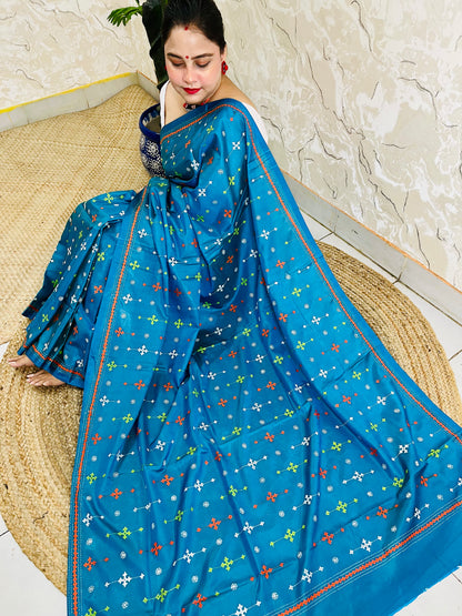 Seated pose in peacock blue saree showing Kutch embroidery pallu spread on silk