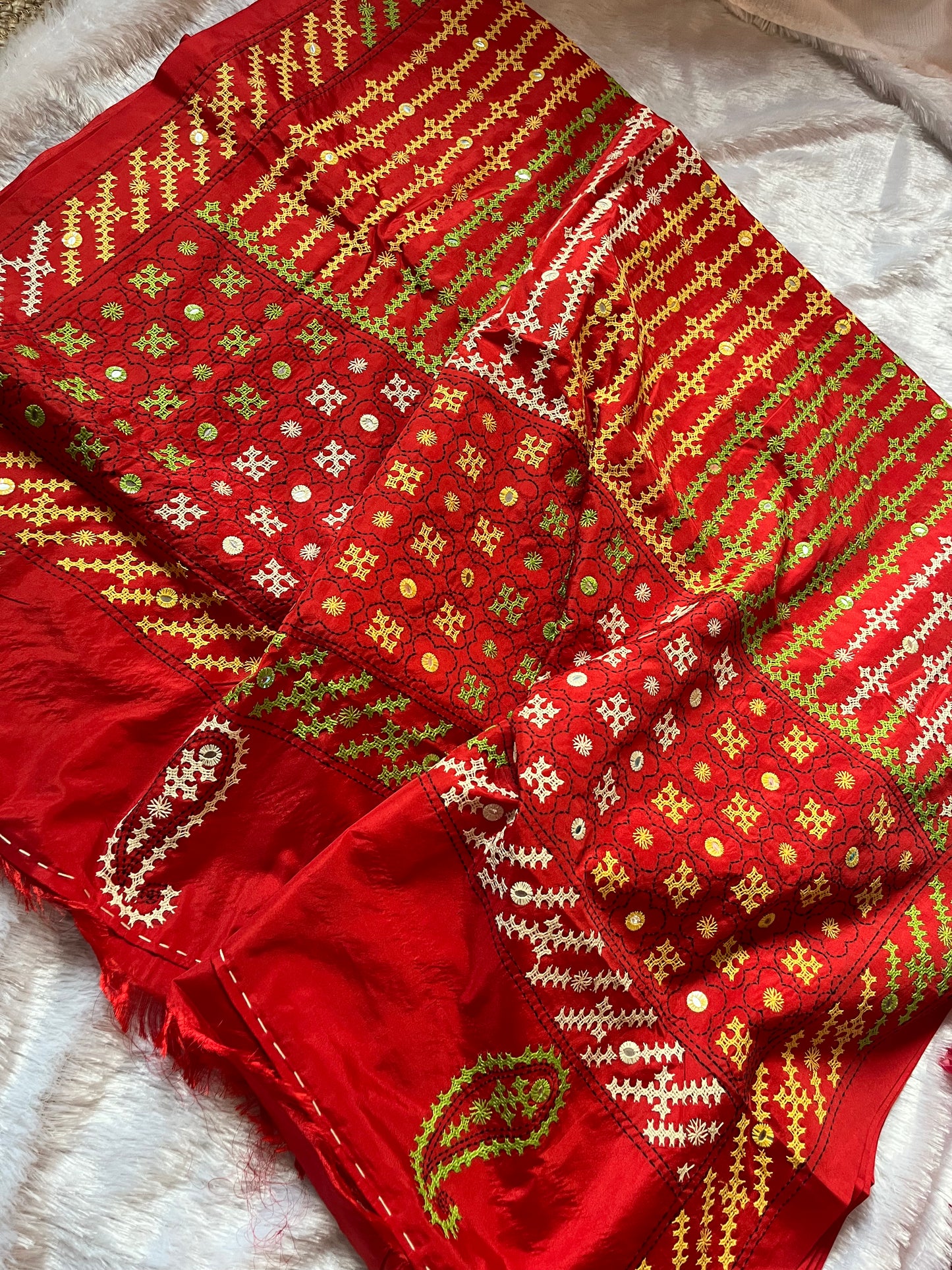 Close-up of multi-color geometric patterns and floral motifs with mirror work on red fabric