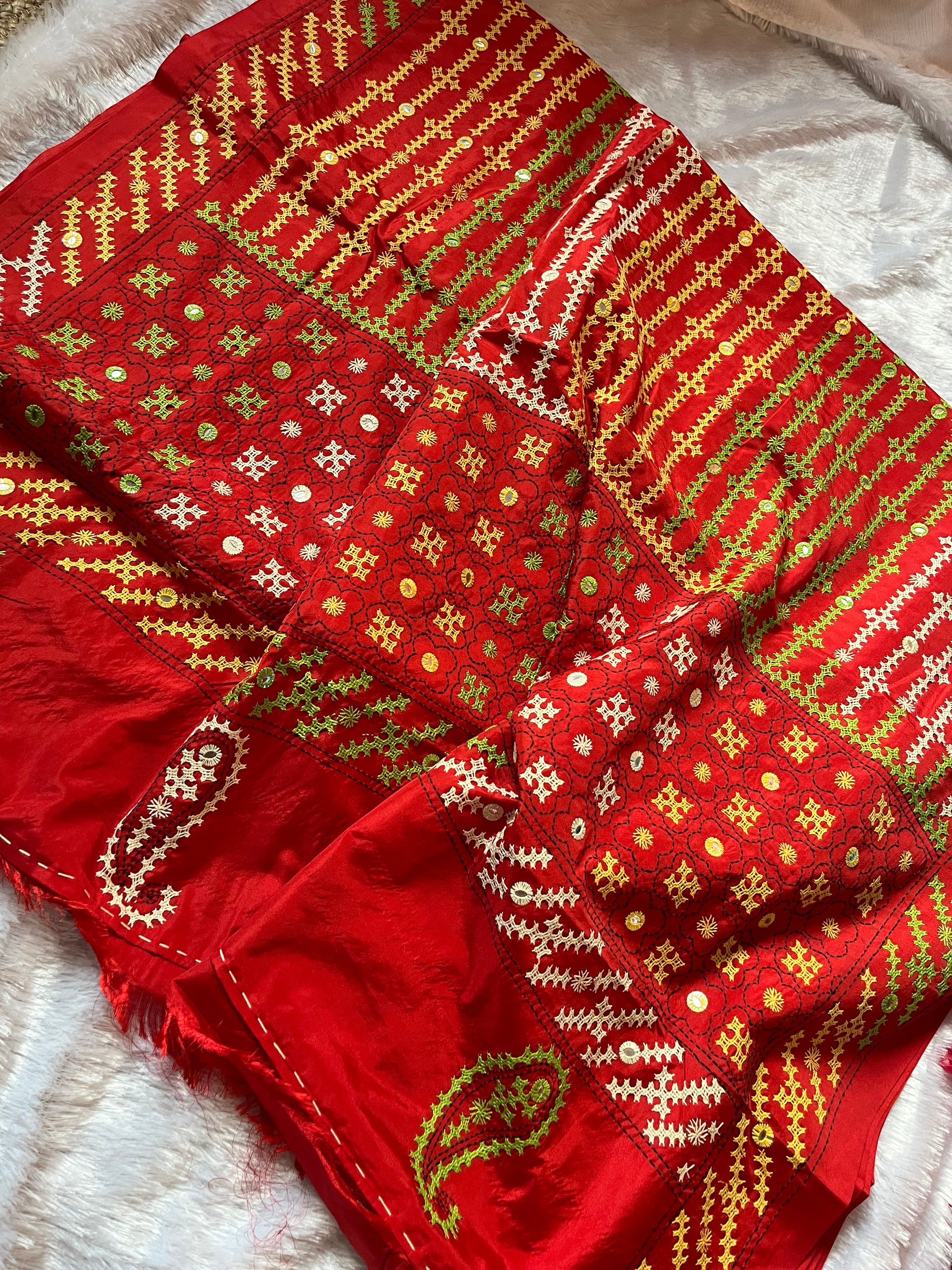 Close-up of multi-color geometric patterns and floral motifs with mirror work on red fabric