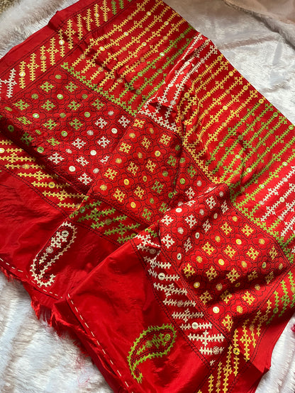 Close-up of multi-color geometric patterns and floral motifs with mirror work on red fabric