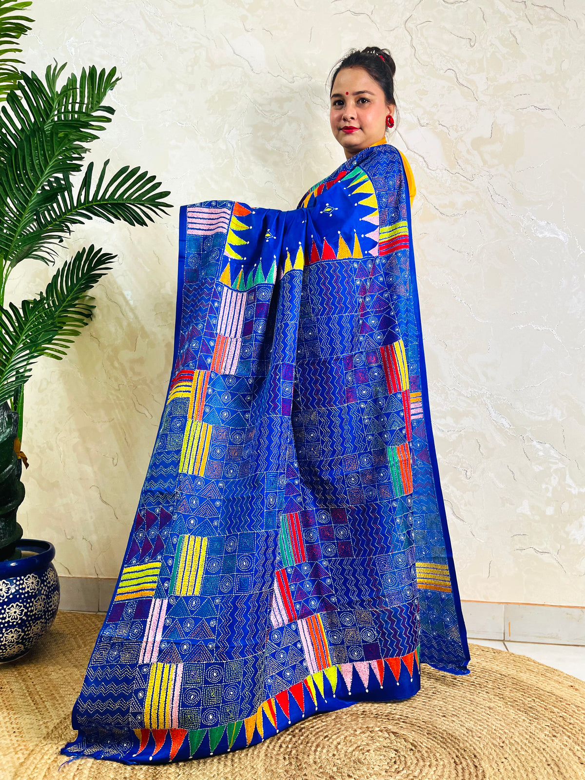 Side standing view of royal blue Kantha stitch saree with colourful pennant border