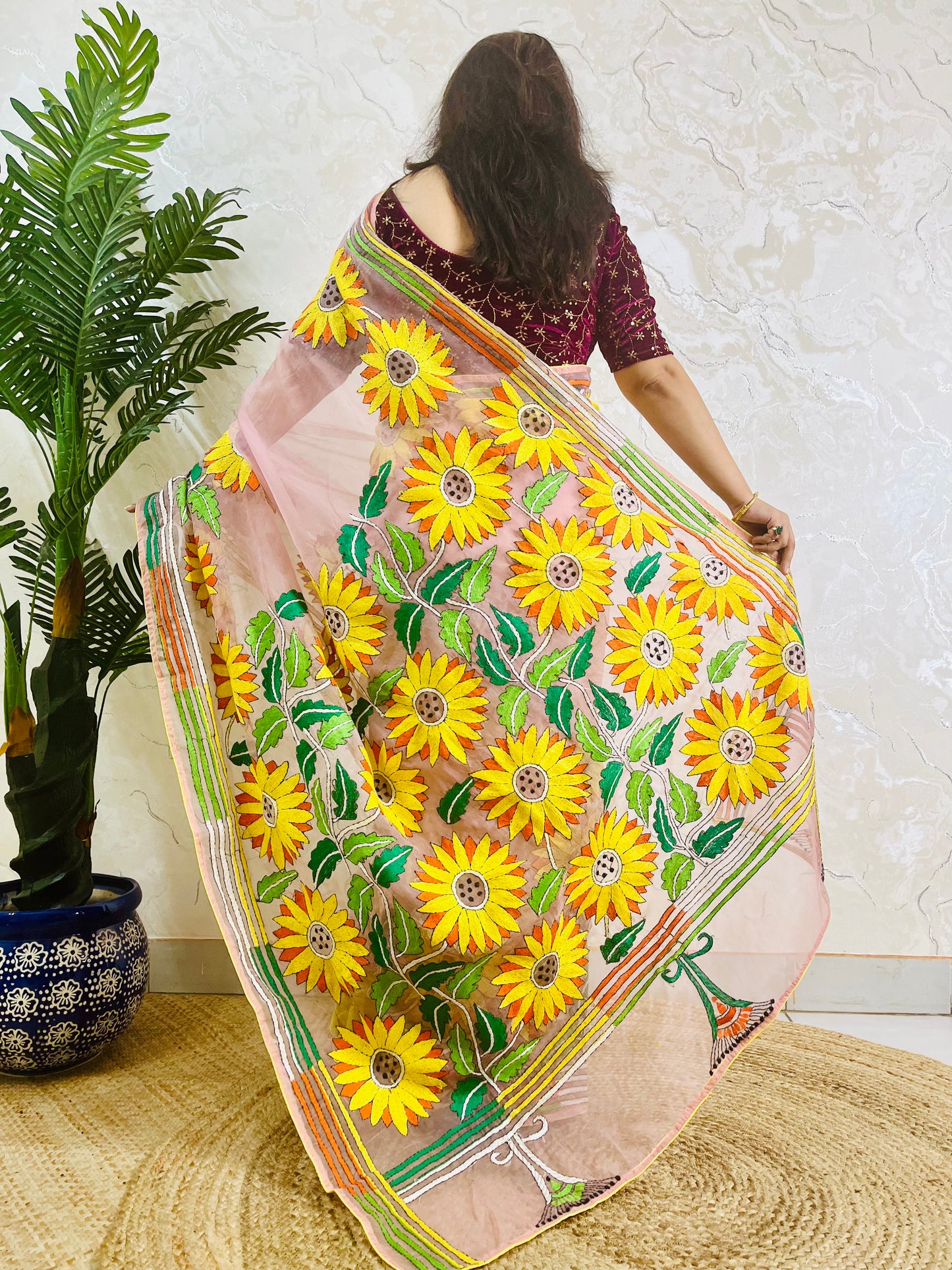Back view of Bengal Kantha stitch blush pink organza saree with bold golden sunflower embroidery and bird border motif displayed in motion — Desi Aadat