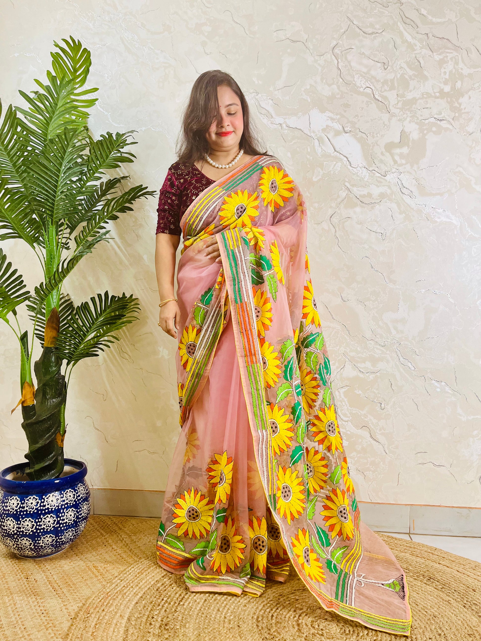 Limited edition blush pink Kantha stitch organza saree with large all-over golden sunflower embroidery and multicolour border — side standing view by Desi Aadat