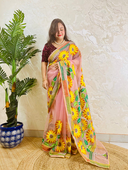 Limited edition blush pink Kantha stitch organza saree with large all-over golden sunflower embroidery and multicolour border — side standing view by Desi Aadat